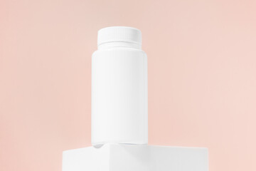 White mockup of a jar of pills or tablets on a peach isolated background. The concept of dietary supplements for health care, pharmacy, vitamins. Image for your design