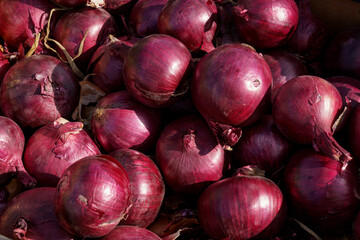 Fresh Red Onions Piled Up At A Market Stall On A Sunny Day