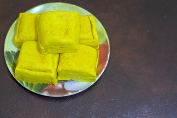 Close up of raw Yellow tofu on wooden plate and soy bean in a plate, with brown background, protein food, stock photo.