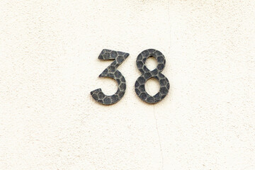 house number 38 in metal at white painted plaster wall