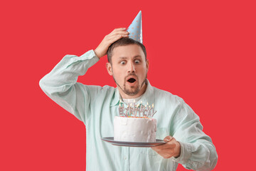 Surprised man with birthday cake on red background