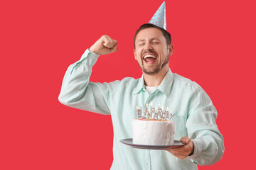 Happy man with birthday cake on red background