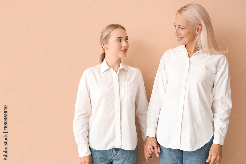 Canvas Prints happy young beautiful woman with her mother holding hands together on orange background