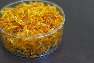 Kentang mustofa, sambal kering kentang or Indonesian cruncy, sweet and spicy potato sticks in plastic jar with brown background, food, stock photo.