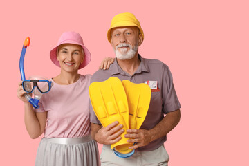Mature couple with snorkeling mask and flippers on pink background. Travel concept