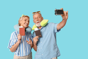 Mature couple with passports taking selfie on blue background. Travel concept