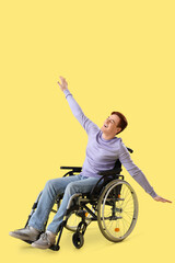 Obraz premium Happy young man in wheelchair on yellow background
