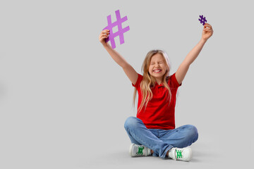 Cute teenage girl with hashtags on grey background