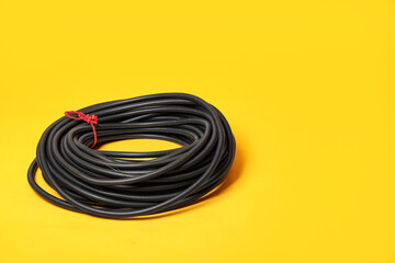 Rolled flexible conduit tube on yellow background, closeup