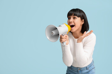 Surprised young woman with megaphone on  blue background