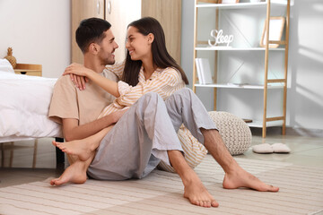 Happy loving young couple sitting near bed