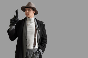 Male spy with gun on grey background