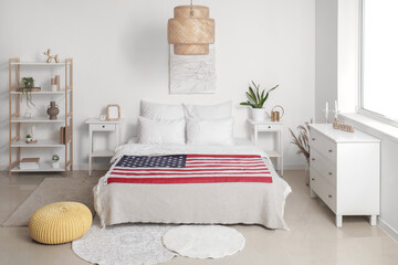 Interior of light bedroom with USA flag on cozy bed