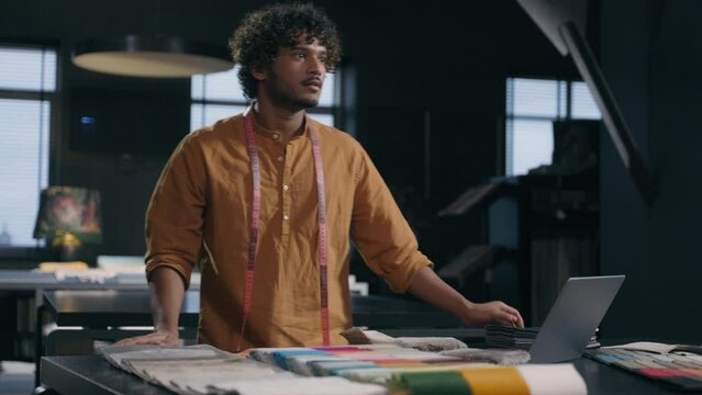 Indian Arabian latino man fashion designer couturier business guy male decorator stylist walk come in tailoring dressmaking studio clothing design shop atelier textile fabric store office happy smile
