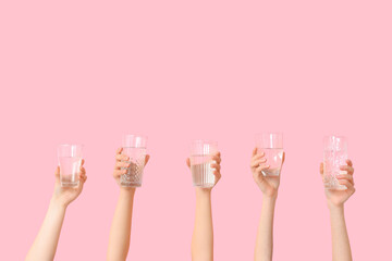 Female hands with different glasses of water on pink background