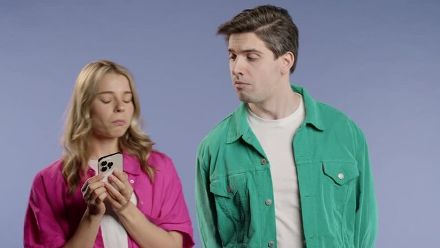 Suspicious man spying on girlfriend chats with smartphone. Jealousy, curiosity