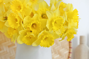 Vase with narcissus flowers in light room, closeup
