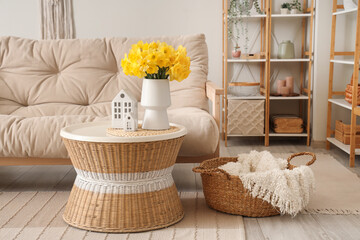 Cozy sofa and coffee table with bouquet of narcissus flowers in beautiful living room