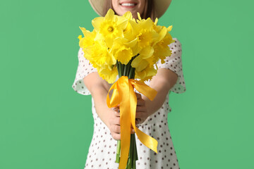 Beautiful young happy woman with bouquet of beautiful narcissus on green background, closeup
