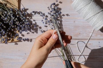 Woman creating bouquets of dry lavender flowers. Process of making scented bouquets and sachet from...