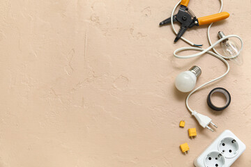 Wire stripper, cable and light bulbs on beige grunge background