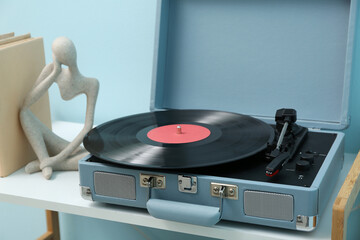 Record player with disk and home decor on shelving unit near blue wall in room