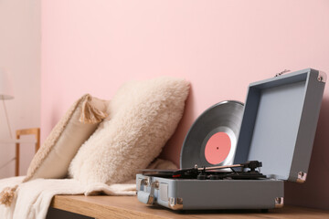 Record player with disk on commode near pink wall in room