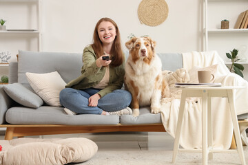 Young woman with cute Australian Shepherd dog watching TV at home