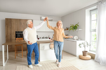 Mature couple dancing on their wedding anniversary in kitchen
