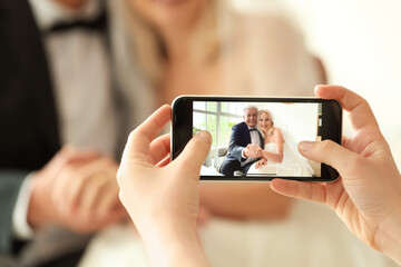 Woman taking picture of mature couple celebrating their wedding anniversary at home, closeup
