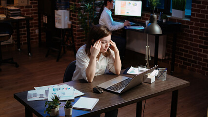 Tired employee struggling to remain focused at workspace desk, feeling overworked and waiting to go...