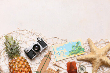 Composition with travel gift voucher, beach accessories, pineapple and fish net on light background