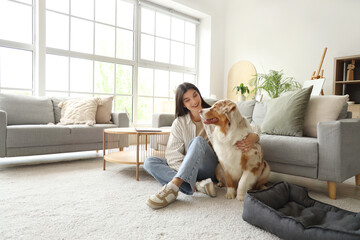 Young woman with Australian Shepherd dog sitting on floor at home