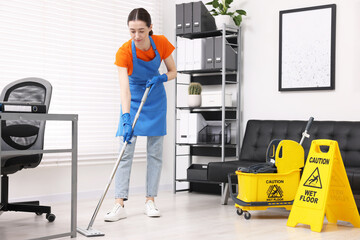 Cleaning service. Woman washing floor with mop in office