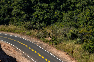 View of an empty paved rural road, flanked by Atlantic forest and eucalyptus fields in a mountain range in Brazil