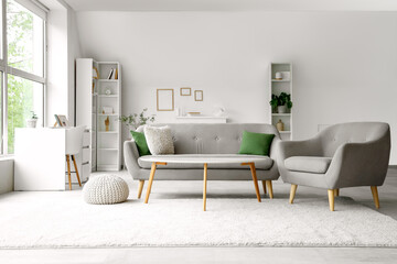 Interior of light living room with grey sofa, armchair and coffee table