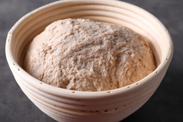 Fresh sourdough in proofing basket on grey table, closeup