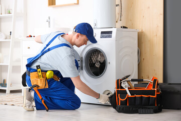 Male technician repairing washing machine in bathroom