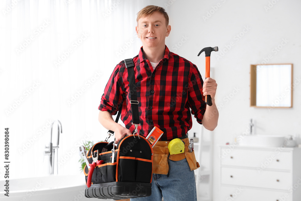 Wall mural Male technician with hammer and bag of tools in bathroom