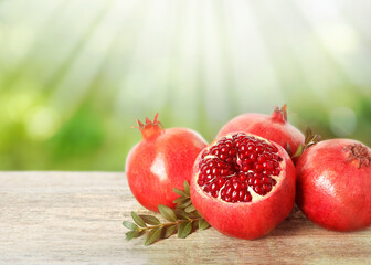 Delicious ripe pomegranates on wooden table against blurred background. Space for text