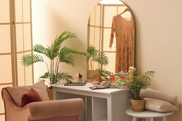 Dressing table with makeup products and palms in room
