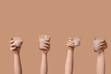 Female hands with glasses of sweet chocolate milk on brown background