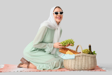 Beautiful young happy woman with food and bottle of wine for picnic in wicker basket sitting on...
