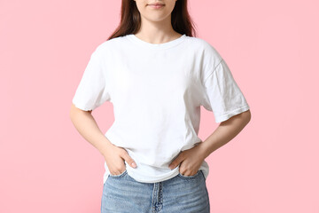 Pretty young woman in stylish white t-shirt on pink background