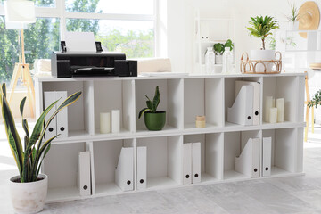 Shelf unit with printer, folders and plants in light office