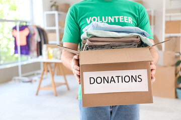 Male volunteer holding donation box with clothes in center, closeup