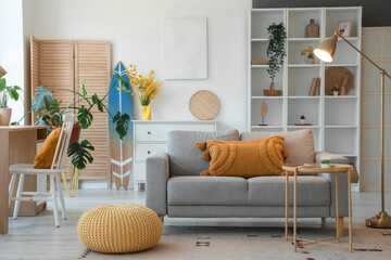 Interior of living room with sofa, workplace and surfboard