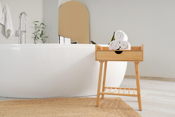Table with towels near bathtub in room