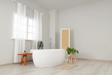 Interior of light room with bathtub, wooden bench and window