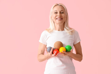 Mature woman with massage balls on pink background